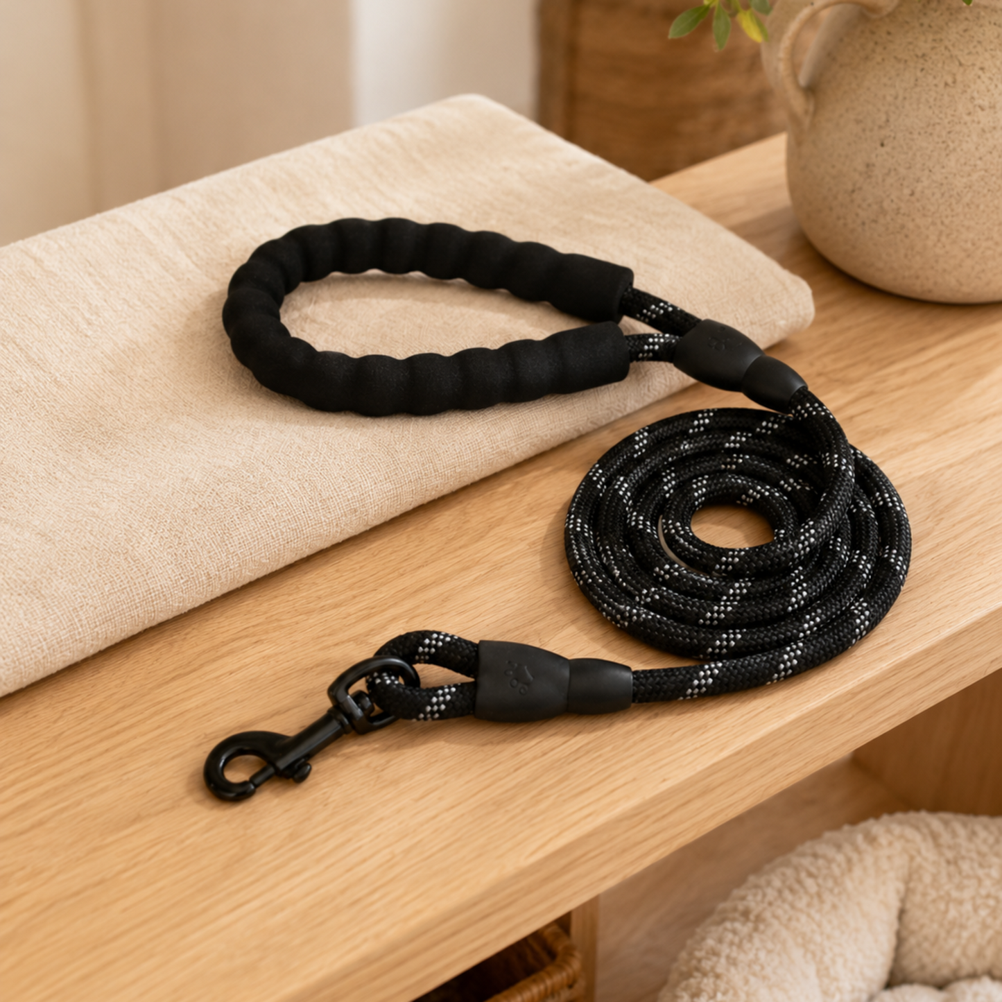 Black dog leash on a wooden surface with a neutral background