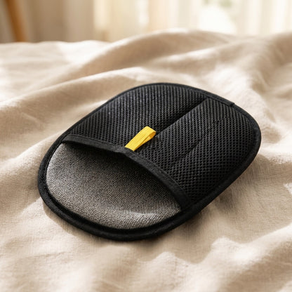 Double-sided pet grooming mitt showing the black mesh back and yellow pull-tab on neutral linen