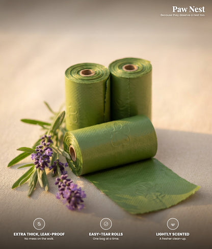 Green dog poop bag rolls with a sprig of lavender on a warm surface. Extra thick and leak-proof, easy-tear rolls, lightly scented.