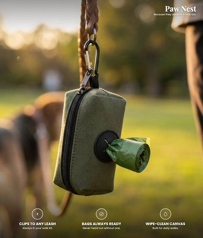 Dog poop bag holder in army green canvas clipped to a leash on a golden-hour walk, with a poop bag pulling through the front dispenser. Clips to any leash, bags always ready, wipe-clean canvas.