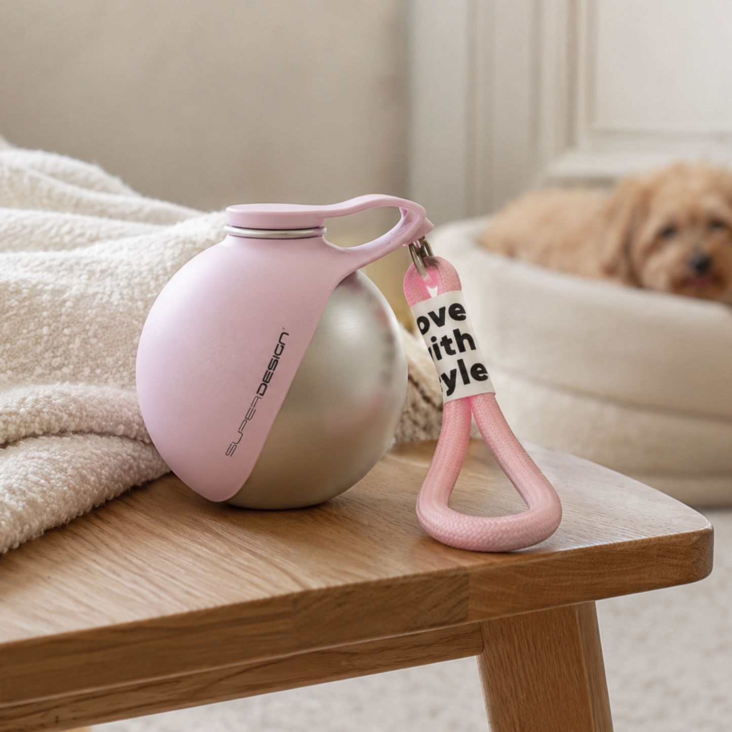 Pink pet leash with a tag on a wooden table, dog in the background